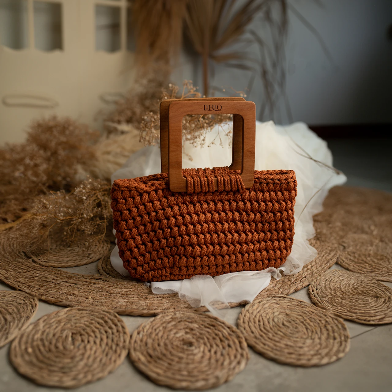 Brown woven handbag with wooden handle on a textured surface